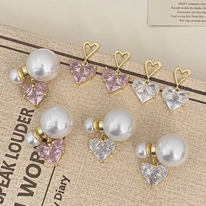 Vue détaillée de boucles d'oreilles cœur rose et perles sur emballage vintage