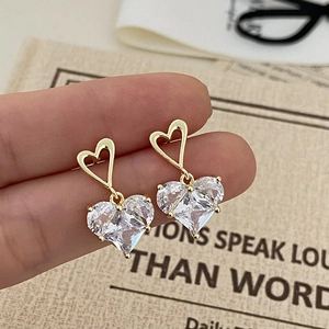 Détail de boucles d'oreilles pendantes cœur rose en cristal sur fond de carte vintage