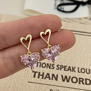 Gros plan détaillé de boucles d'oreilles perles roses en forme de cœur doré