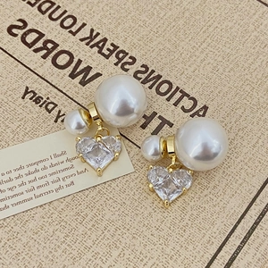 Détail de boucles d'oreilles cœur rose avec double perles sur fond d'écriture vintage