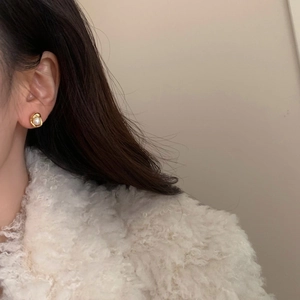 Dettaglio orecchini con perle d'acqua dolce e base dorata effetto lava indossati da modella