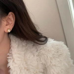 Dettaglio dell'orecchino di perla dorata stile lava indossato da una modella con eleganza