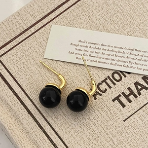 Detailed view of vintage gold stud earrings with large black spherical beads on poetry card