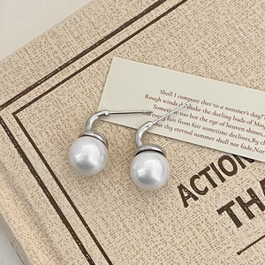 Macro detail of large white pearl drop earrings with elegant silver J-shaped hooks
