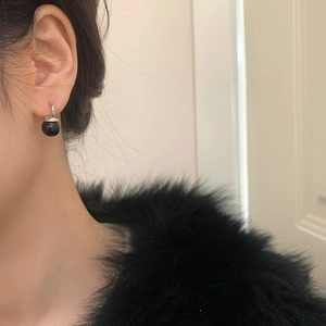 Close-up of elegant black pearl drop earring with silver ring on model with fur collar