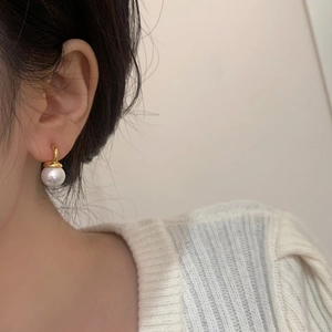 Elegant pearl drop earring with gold hook shown on model with white sweater