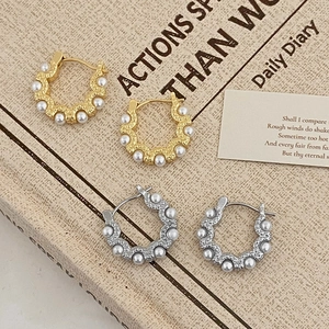Elegant gold and silver wavy hoop earrings with embedded pearls shown in a top view