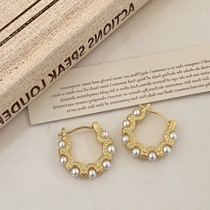 Detailed shot of retro gold hoop earrings with small pearls and wavy fan edges