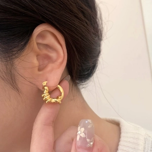 Orecchini a cerchio intrecciati dorati minimalisti indossati da una modella elegante