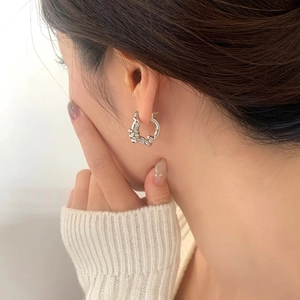 Eleganti orecchini a cerchio ritorti in argento per donna indossati da una modella in stile