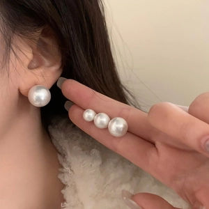 Set of four classic round pearl stud earrings in various sizes shown on ear