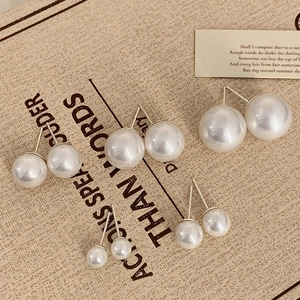 Detail view of five pairs of lustrous white pearl earrings in various sizes on linen background