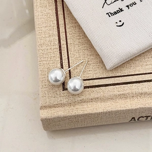 Close-up of classic round white pearl earrings on a book with soft natural lighting