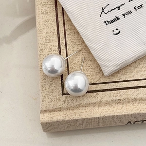 Detailed view of large white pearl earrings placed on a vintage book with soft lighting