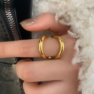 Close-up of a chunky gold minimalist double-arc open ring worn on a finger