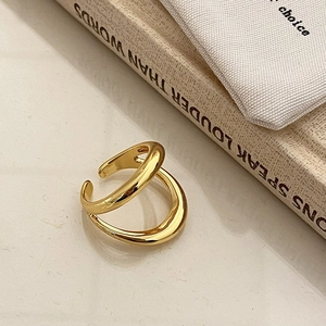 Close-up of golden double-layer streamlined open ring with polished metallic finish