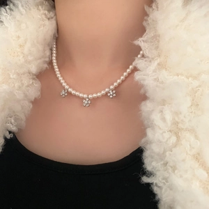 Gros plan d'un collier de perles avec fleurs en zircon sur une tenue d'hiver élégante