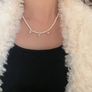 Gros plan d'un collier de perles élégant avec trois pendentifs fleurs en zircon sur le cou