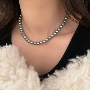 Élégant collier de perles grises rondes pour femmes, porté sur une tenue noire et blanche