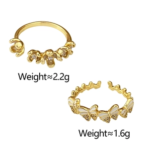 Close-up of golden floral and butterfly rings with white enamel and sparkling crystals