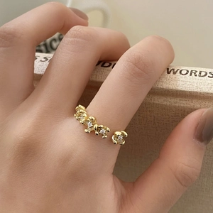 Close-up of adjustable golden flower ring with enamel petals and zircon on hand