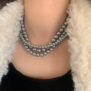 Gros plan d'un collier de perles grises multicouche élégant au lustre métallique