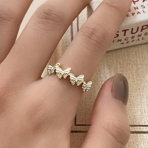 Detail of adjustable golden butterfly ring with white enamel wings and pavé zircons