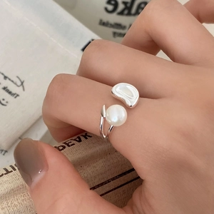 Minimalist open pearl ring with organic silver metal leaf on vintage book background