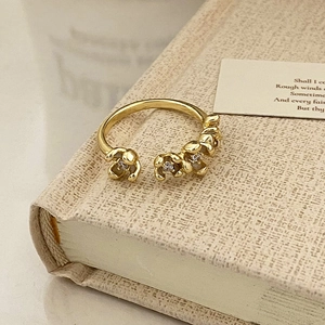 Detailed view of an adjustable gold flower ring with small white crystals on a vintage book