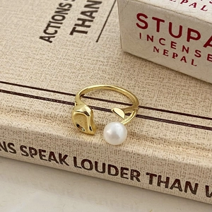 Detailed shot of golden freshwater pearl open ring on vintage book with droplet texture