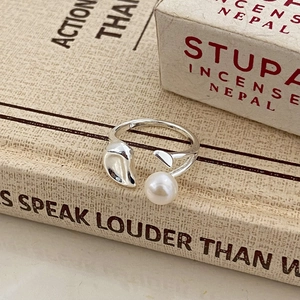 Detailed view of silver freshwater pearl ring with organic leaf design on vintage books