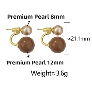 Dettaglio di orecchini a doppia perla con perle crema e marroni su montatura dorata