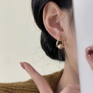Élégantes boucles d'oreilles créoles dorées torsadées avec perle rose sur le mannequin