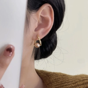 Boucles d'oreilles créoles dorées avec perle champagne portées par un mannequin