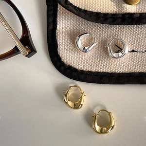 Irregular gold and silver hoop earrings with organic molten texture on a minimalist display