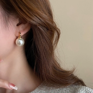 Elegant French vintage white pearl drop earrings with gold hooks on a female model