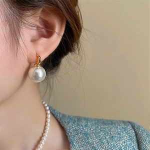 Close-up of model wearing elegant vintage pearl earrings and matching necklace