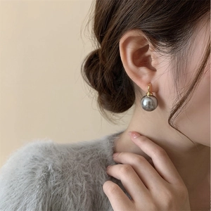Detail of grey pearl drop earring with gold hook on model showing elegant french style