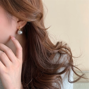 Detail shot of a mirror grey pearl drop earring on a model with gold hoop accent