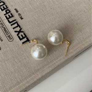 French vintage elegant pearl stud earrings with gold pins on textured background