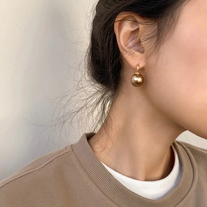 Close-up of golden sphere drop earrings worn by a model showing the elegant drop effect