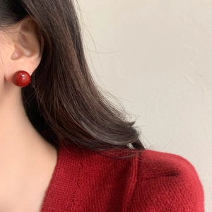 Close-up of retro red pearl stud earring on model wearing matching red sweater