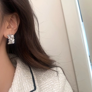 Elegant multi-layered silver zircon and pearl drop earrings worn by a model
