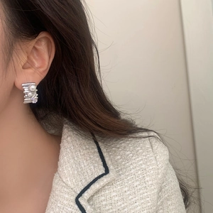 Detail of silver stud earring with white pearls and purple gemstone on model