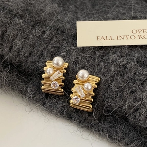 Detailed shot of golden earrings with layered metal, pearls, and cubic zirconia stones