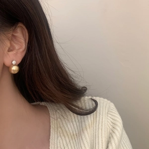 Elegant gold pearl stud earrings with zircon accent shown on a model's ear