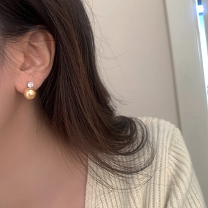 Elegant gold pearl stud earrings with zircon inlay worn by a model in a side profile shot