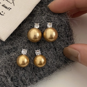Vintage golden pearl earrings set with sparkling zircon on a dark textured background