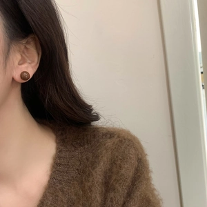 Close-up of a model wearing brown spherical stud earrings with a glossy mirror finish