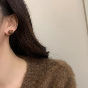 Close-up of vintage brown enamel round stud earrings worn with a textured sweater